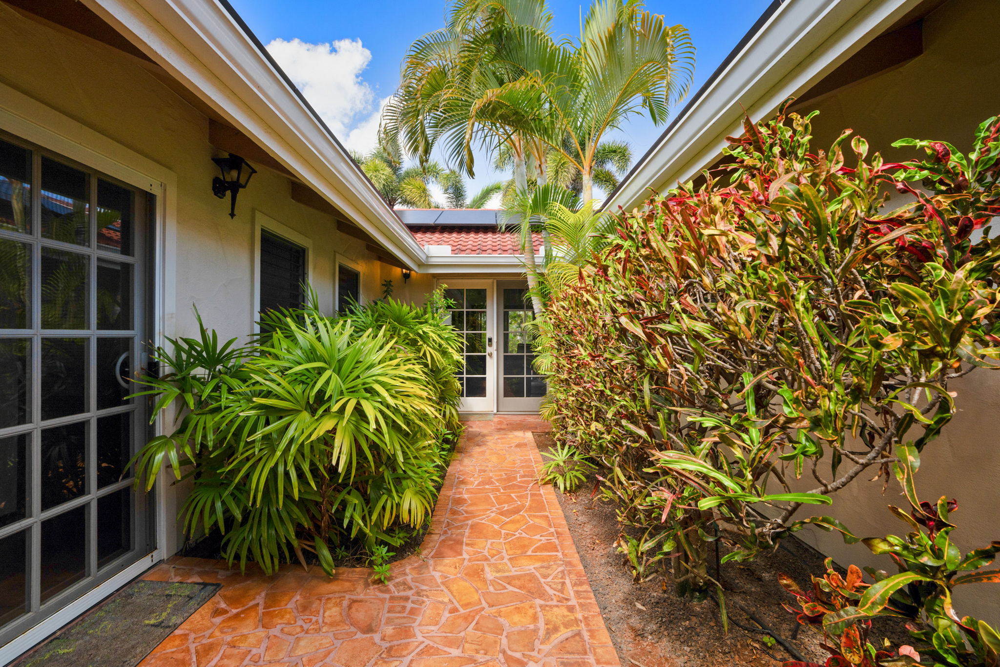 Entryway: Welcoming covered entry with tropical landscaping